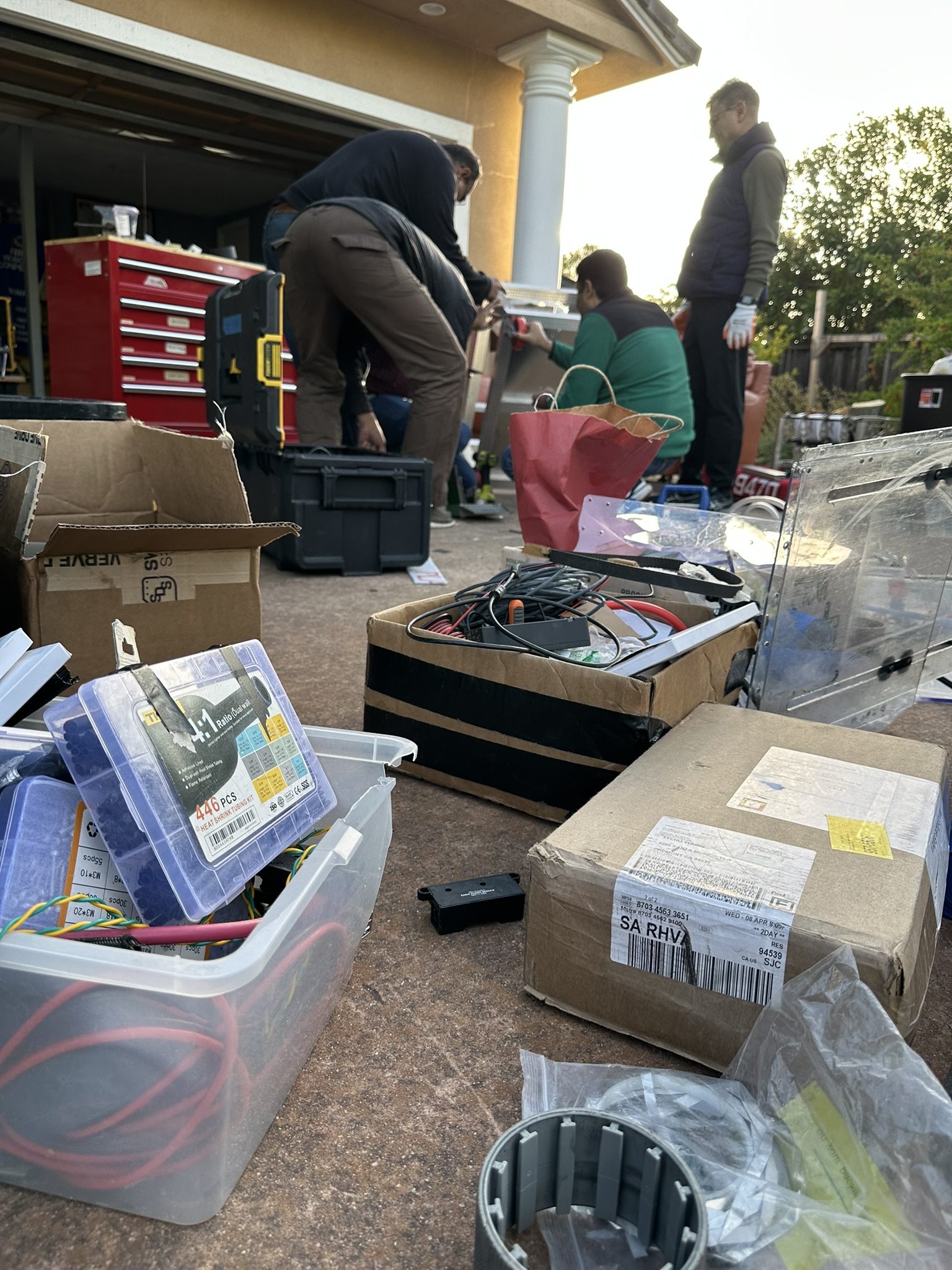 Team working outside the garage among tools and robot parts