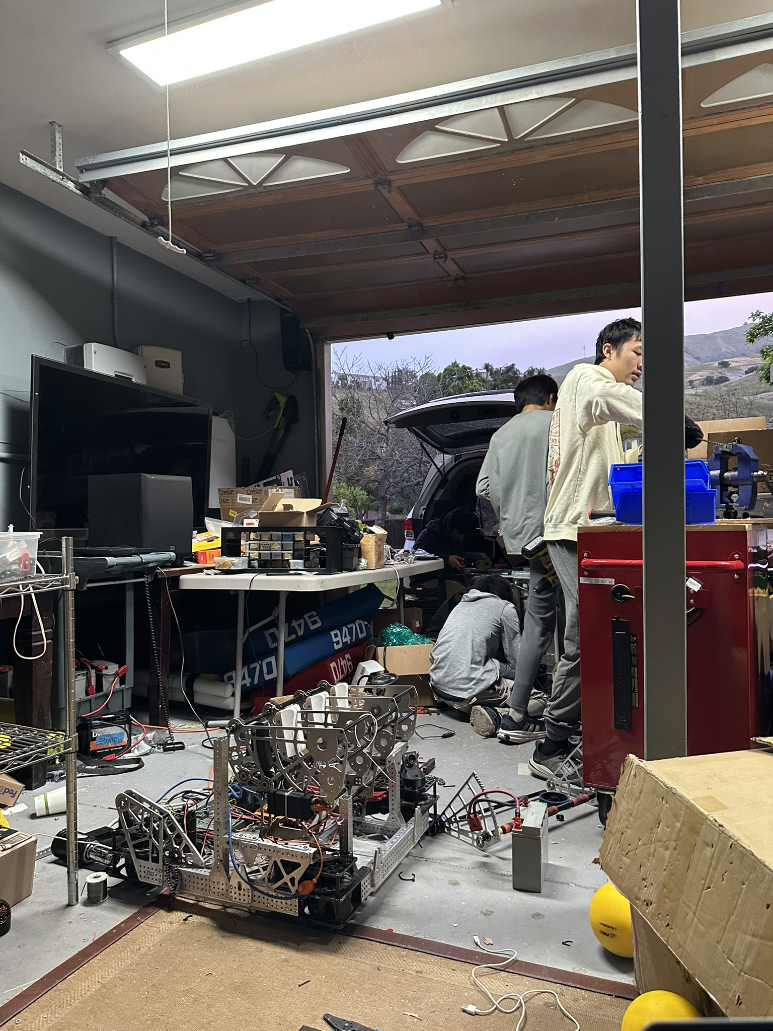 Robot under construction with team members working in the garage