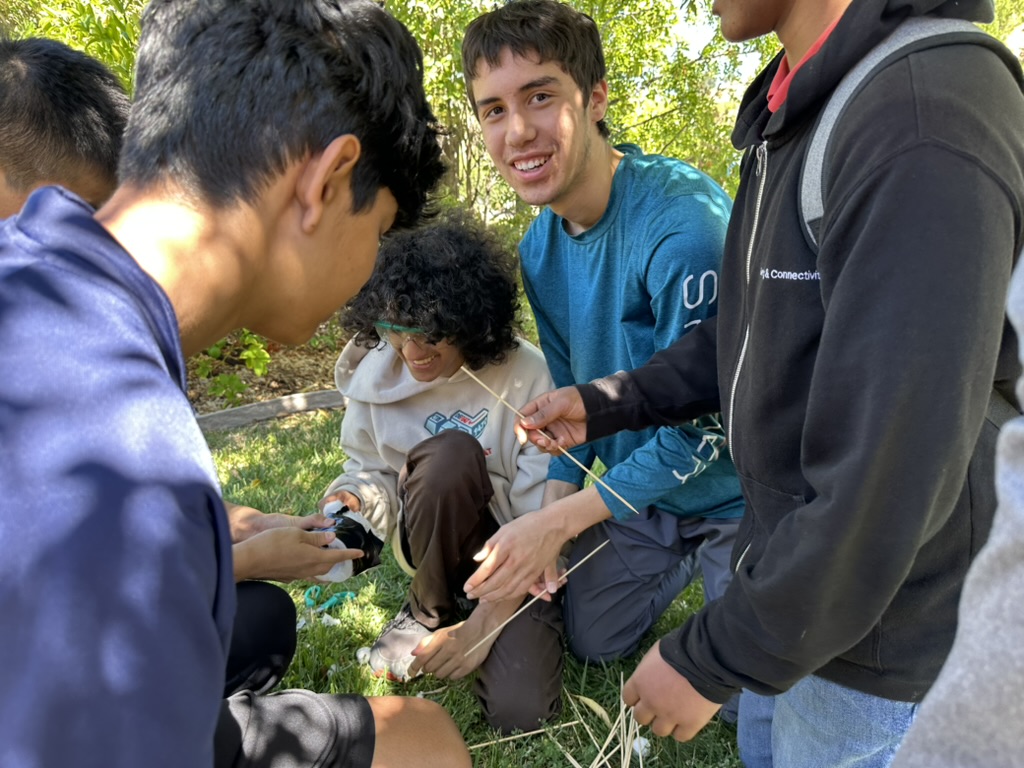 Team members building with wooden sticks outdoors